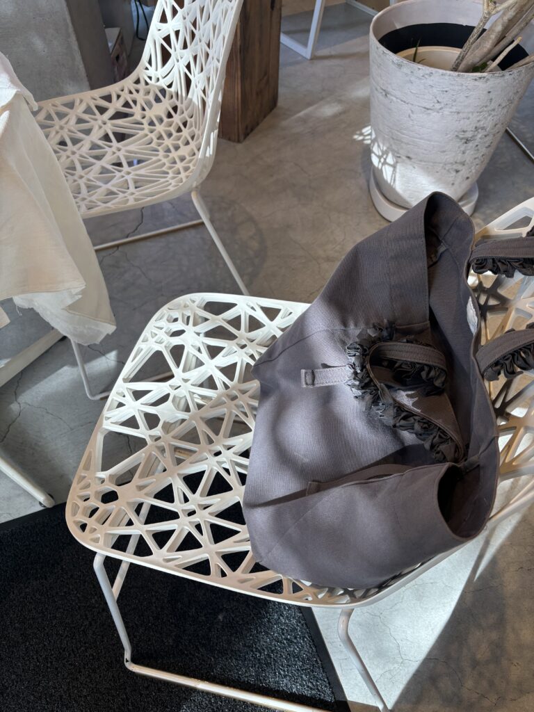白いデザインチェアの上に置かれた、中古で購入したお気に入りのグレーバッグの写真