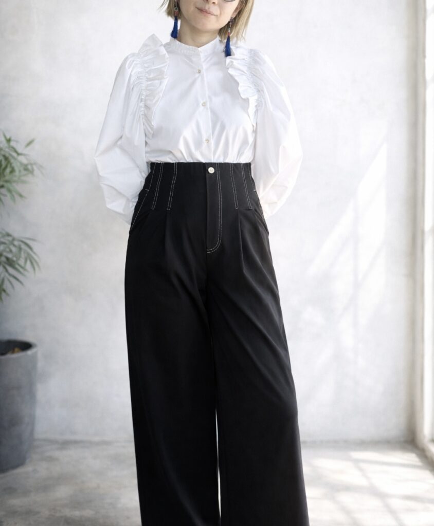 フリルとパフスリーブの白ブラウスに、ステッチ入り黒ワイドパンツを合わせた大人カジュアルコーデ